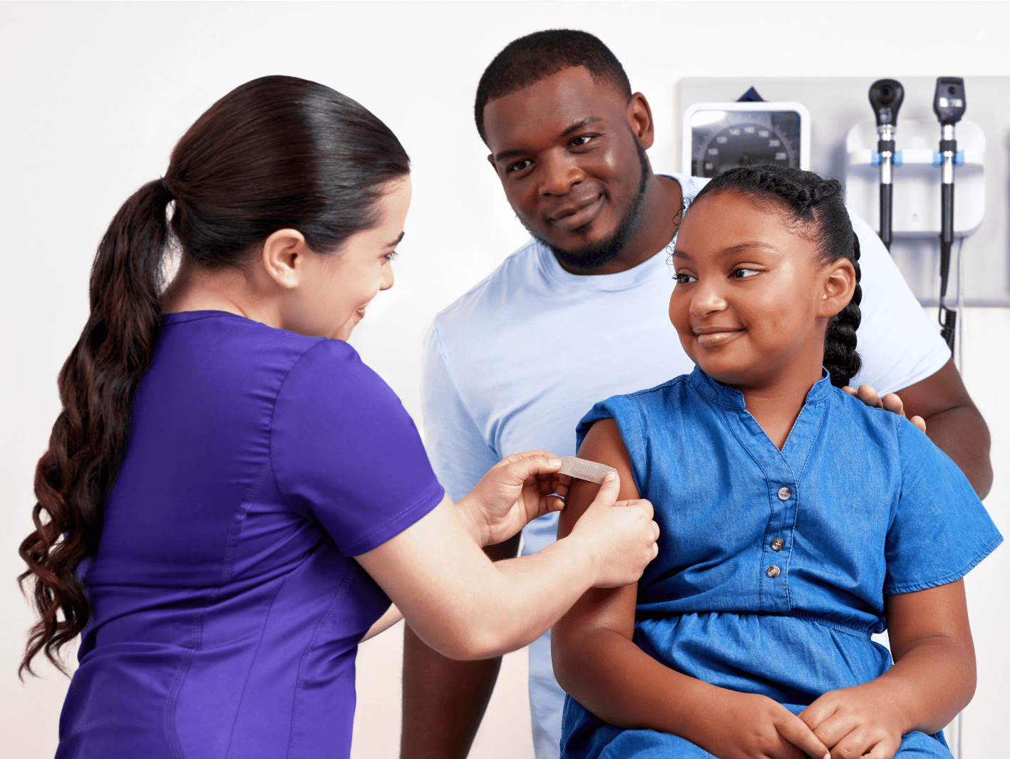 A nurse putting a bandage onto the arm of a pediatric patient after she has received a vaccination.