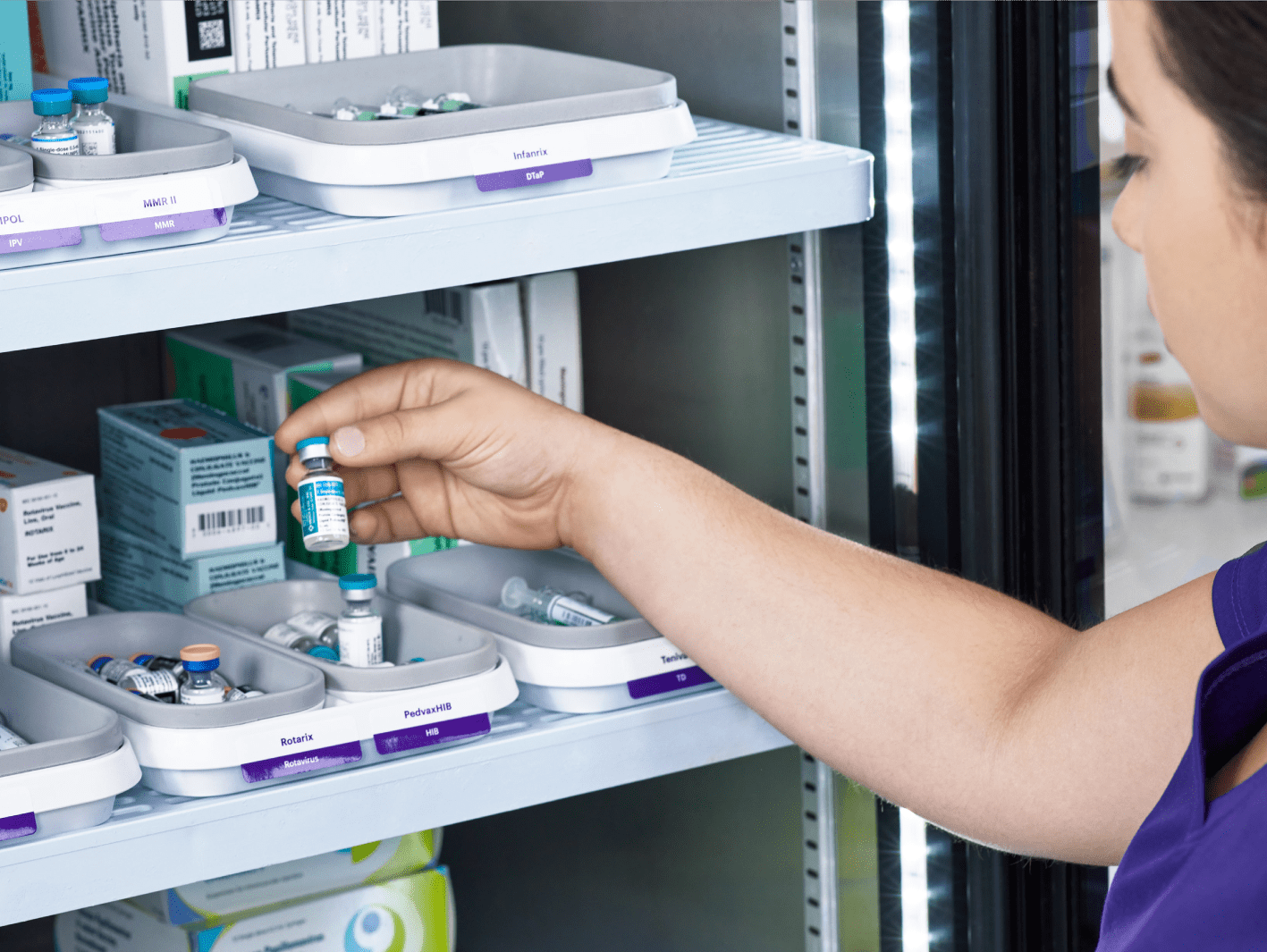 A nurse removing a single dose vial (SDV) vaccine from a vaccine refrigerator.