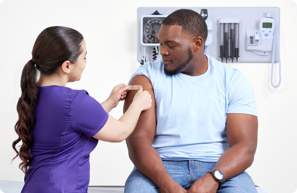 A nurse places a bandage on their patient's arm after a vaccination